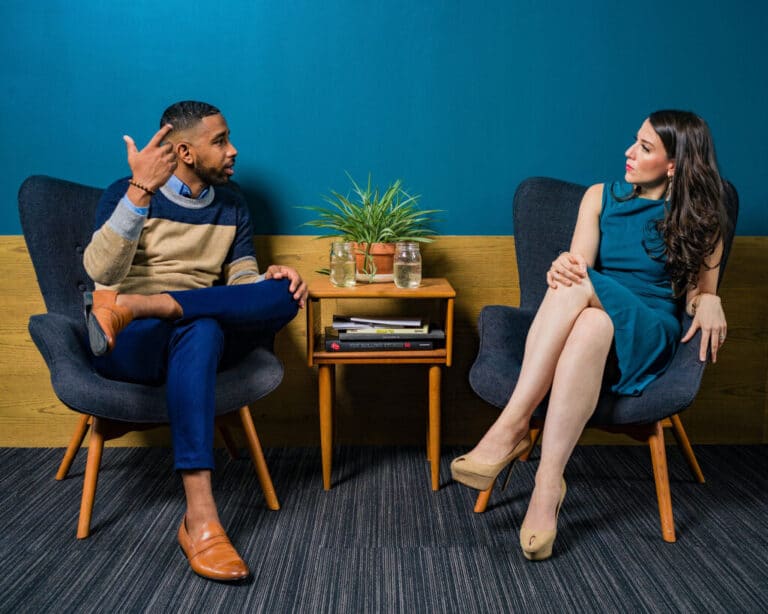 man and woman sitting on chairs talking to each other